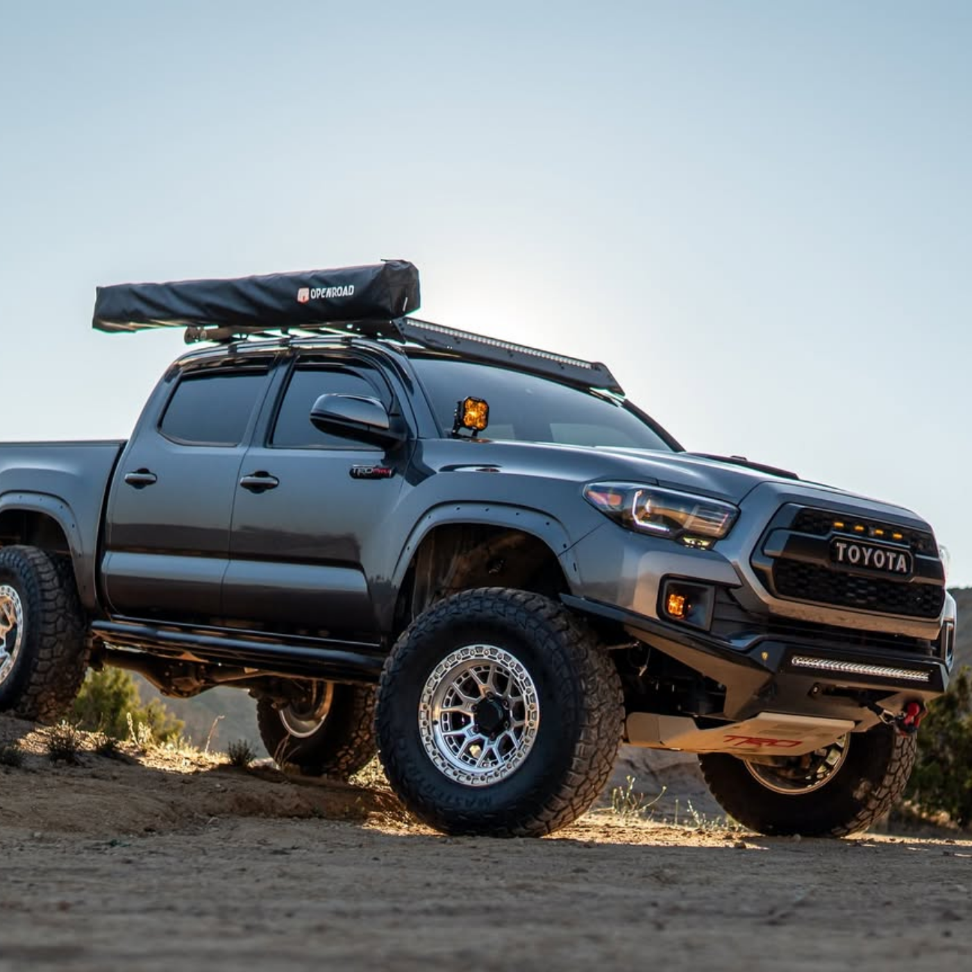 Toyota truck with roof rack and off-road tires on a dirt road